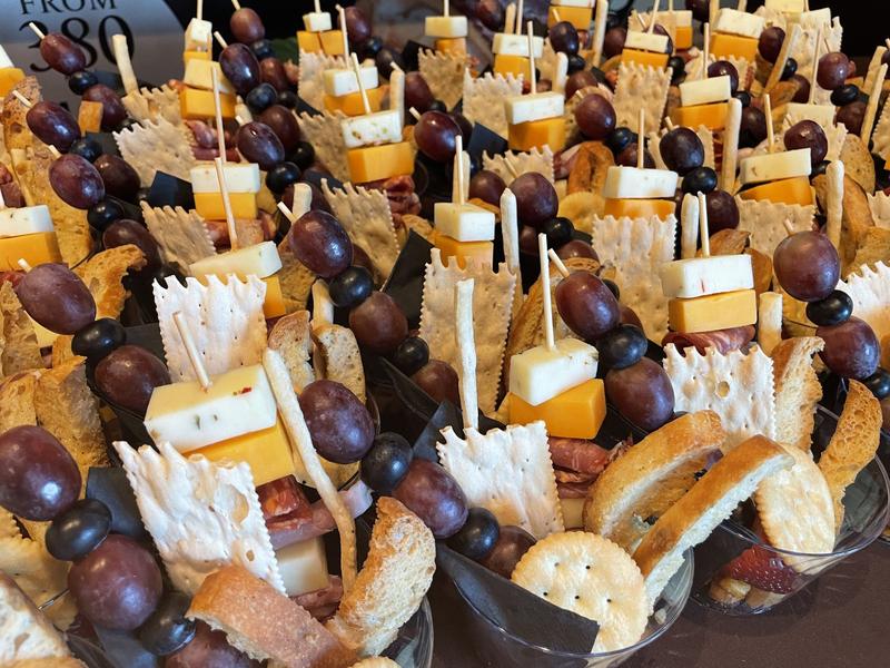 Individual charcuterie cups with cheese and grape skewers, crackers and crostini