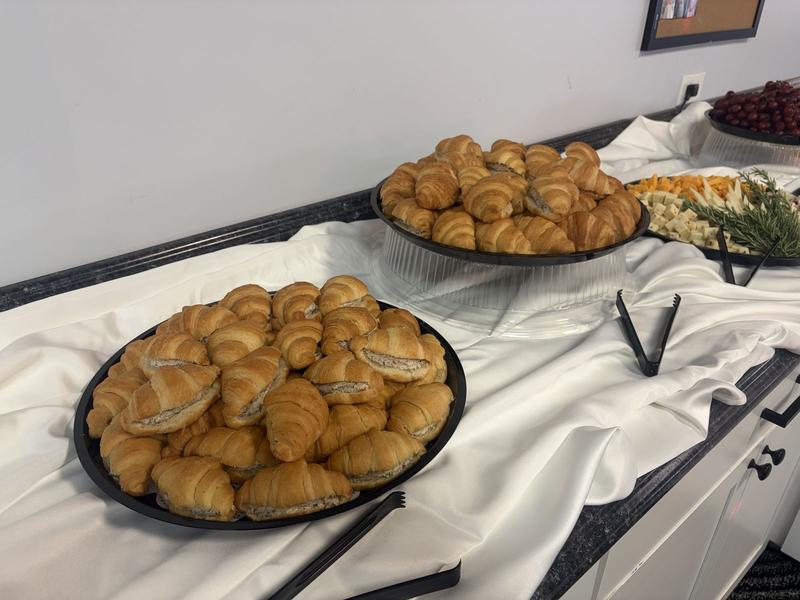 Platters of chicken salad croissants on a white-draped serving table