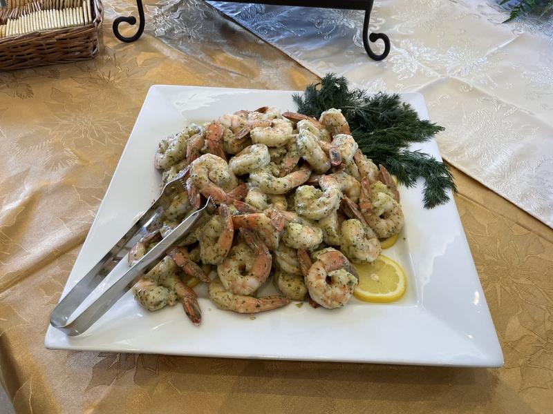 Platter of dill Dijon shrimp cocktail with lemon and fresh dill on a gold tablecloth