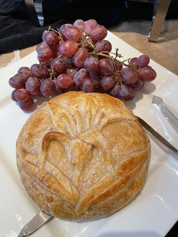 Golden baked brie in a decorative pastry crust, served with red grapes
