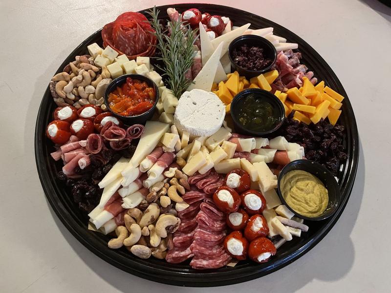 Round platter of cured meats, cheeses, nuts, stuffed mini peppers and small bowls of dips