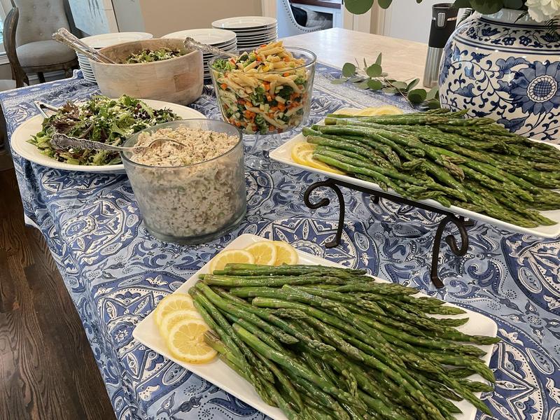 Catered table with asparagus platters and salads on a blue-and-white tablecloth