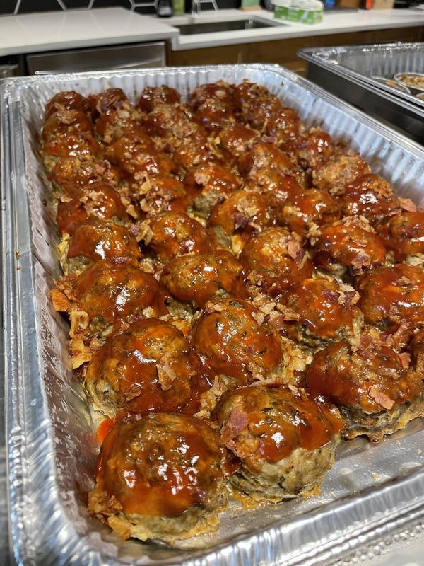 Foil pan of individual bacon-topped meatloaves with a glaze