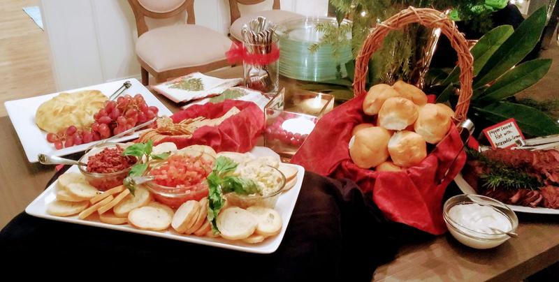 Catered buffet with a basket of dinner rolls and appetizer platters