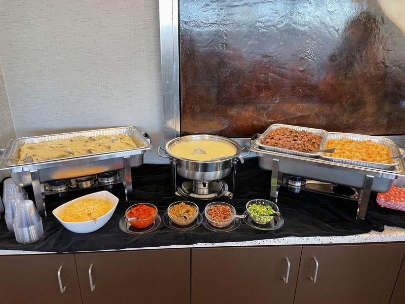 Mashed potatoes bar with chafing dishes and bowls of toppings