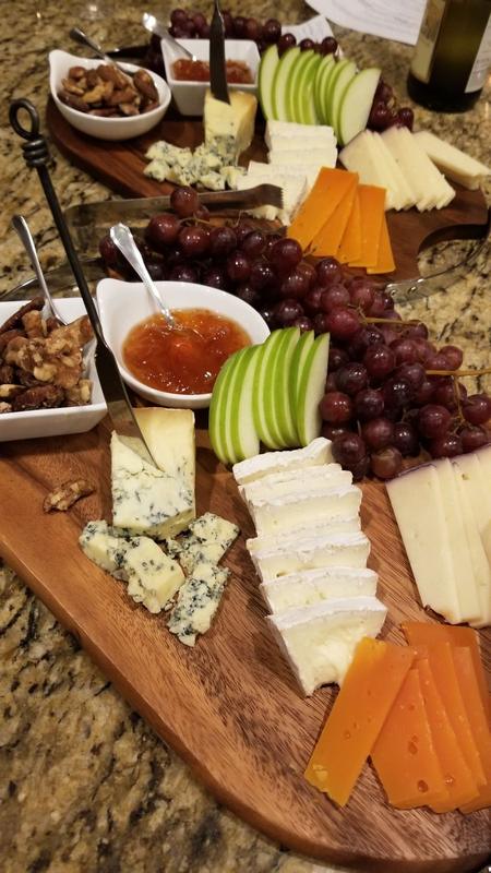 Board of assorted cheeses with grapes, apple slices and crackers
