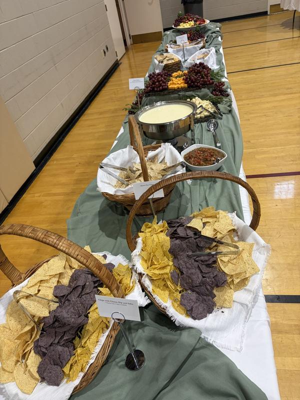 Long buffet table with cheese dip, fresh salsa and baskets of chips