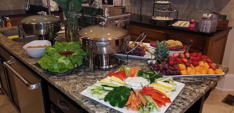 Home party buffet with chafing dishes and a fresh vegetable platter