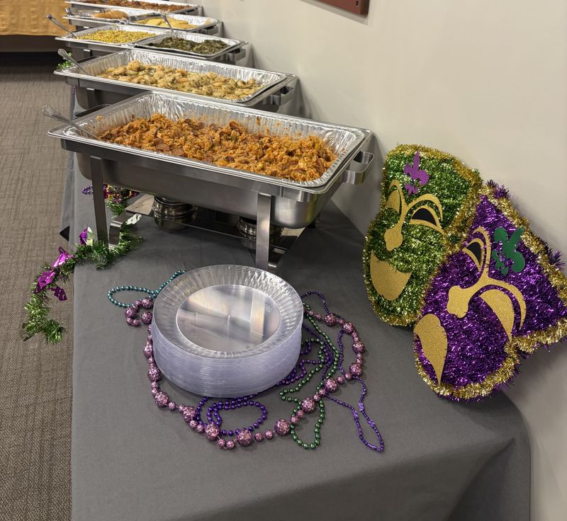 Mardi Gras themed buffet with chafing dishes, beads and a mask