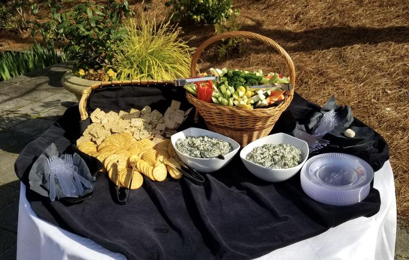 Catered table set up outdoors with dips and a vegetable basket