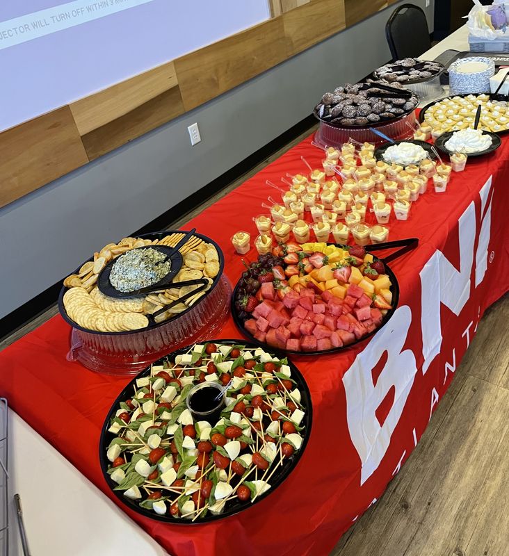 Red-draped buffet with caprese skewers, spinach dip with crackers, fresh fruit and individual dessert cups