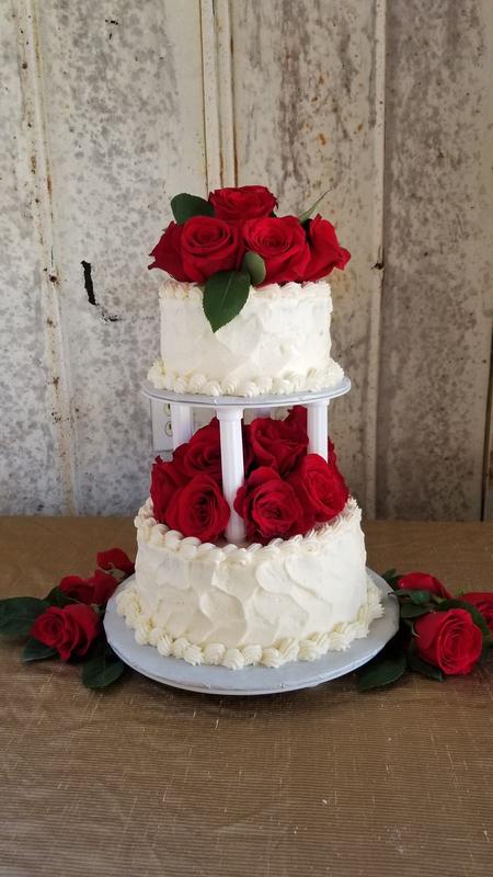 Tiered white celebration cake decorated with red roses