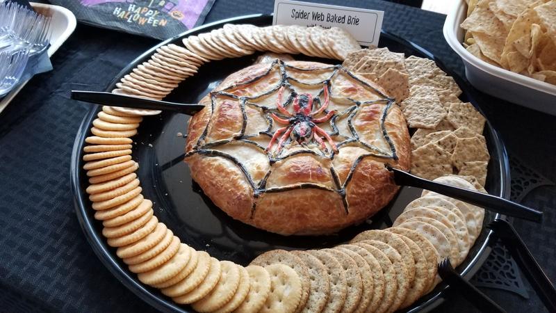 Halloween baked brie decorated with a spiderweb, surrounded by crackers