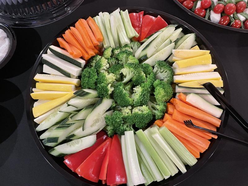 Round platter of fresh vegetables arranged around broccoli