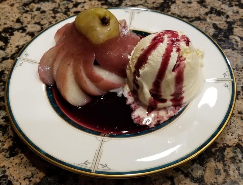 Poached pear with vanilla ice cream and berry sauce