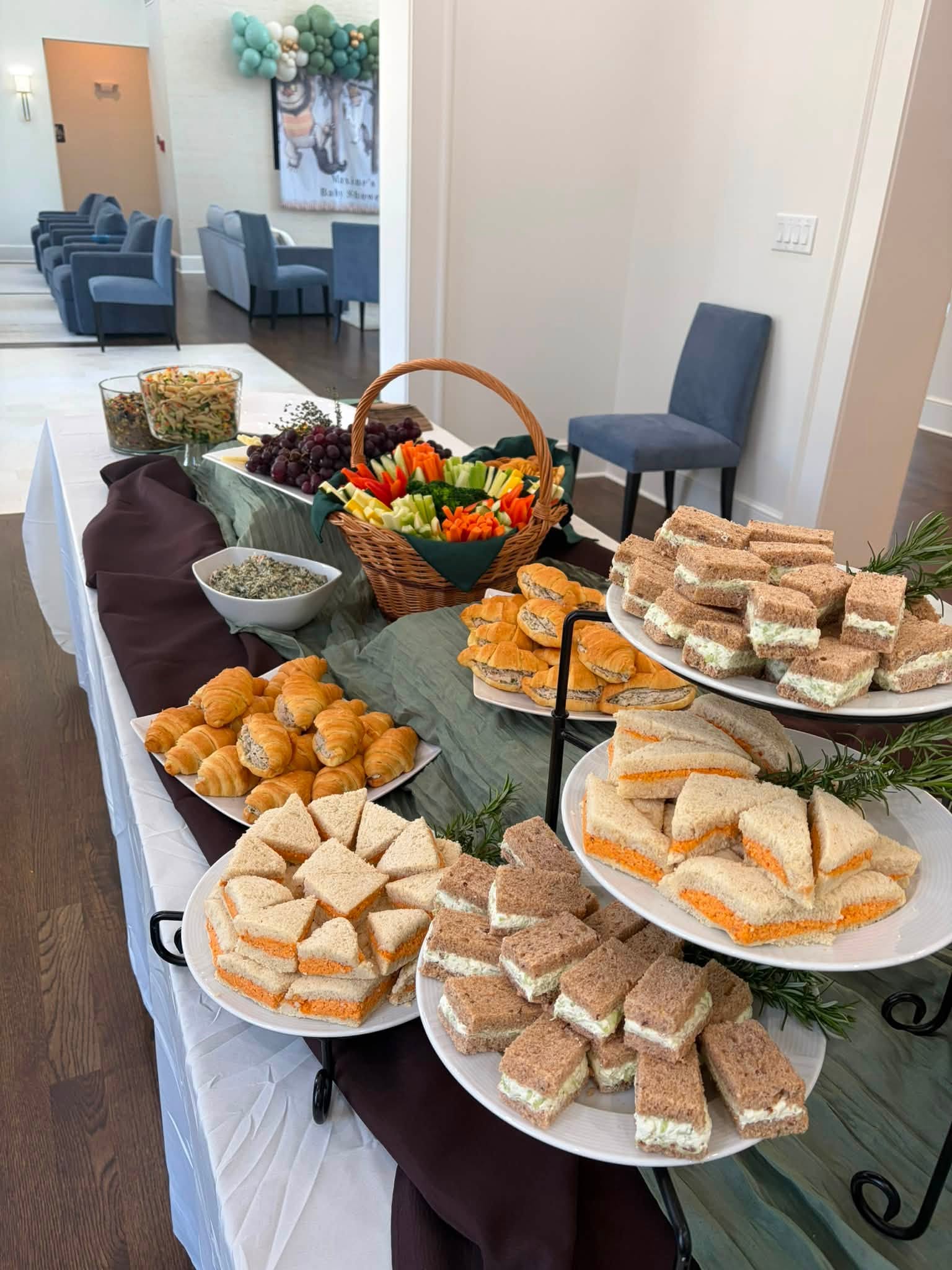 Catering spread with tea sandwiches, croissants and a fresh vegetable basket