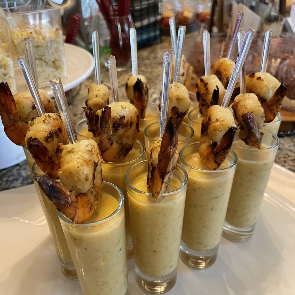 Grilled shrimp served on skewers in small glasses of creamy soup